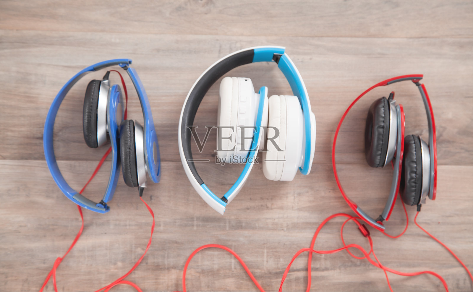木制背景上的蓝色，白色，红色耳机。照片摄影图片