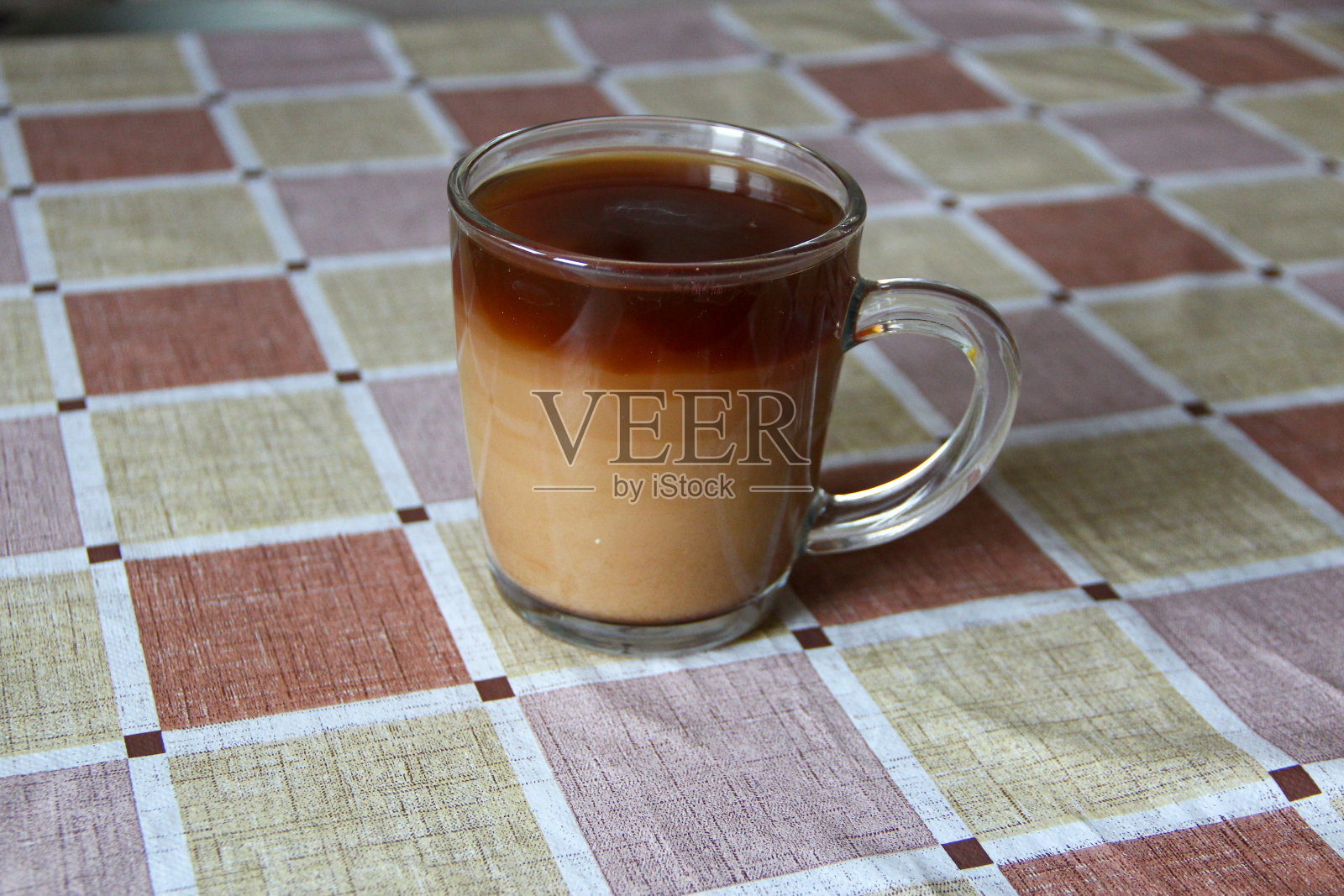 透明咖啡杯加牛奶，饮料的颜色一层层变化照片摄影图片