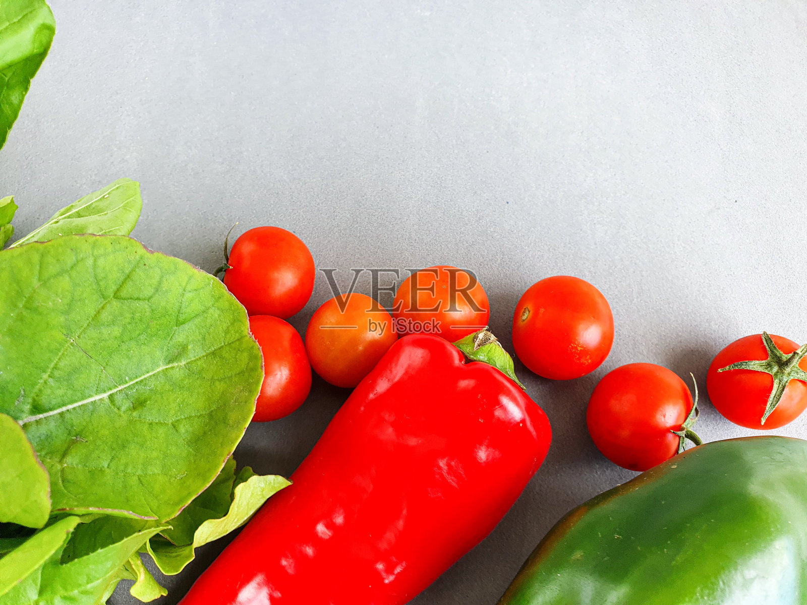 灰色背景上的新鲜蔬菜。圣女果，红辣椒，青椒，芝麻菜。俯视图照片摄影图片