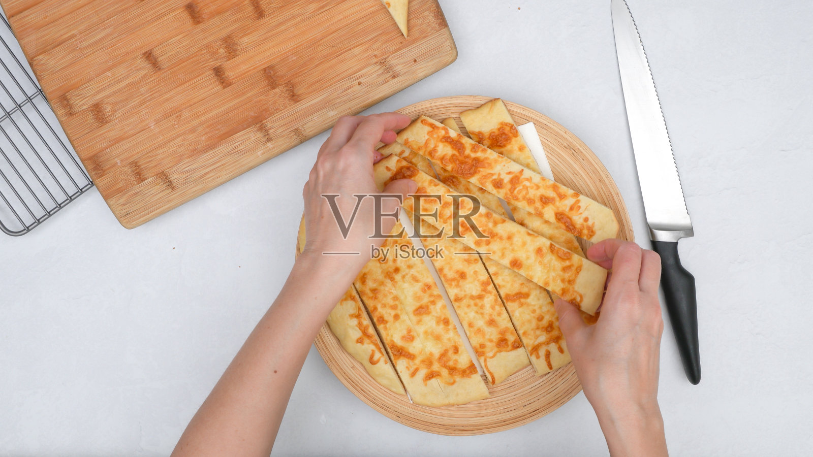 新鲜出炉的自制扁面包片和马苏里拉奶酪贴在木板上，从上面看，女人的手照片摄影图片
