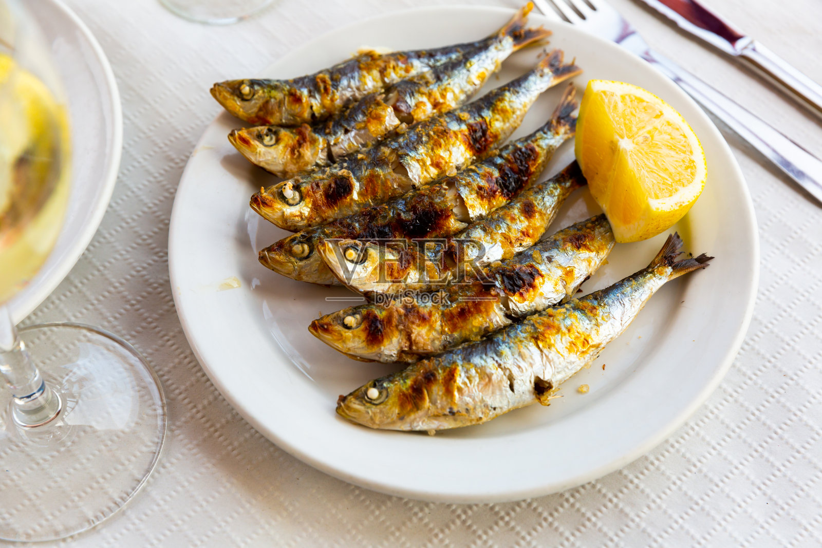 马拉加菜烤沙丁鱼与柠檬在白色盘子在木桌上照片摄影图片