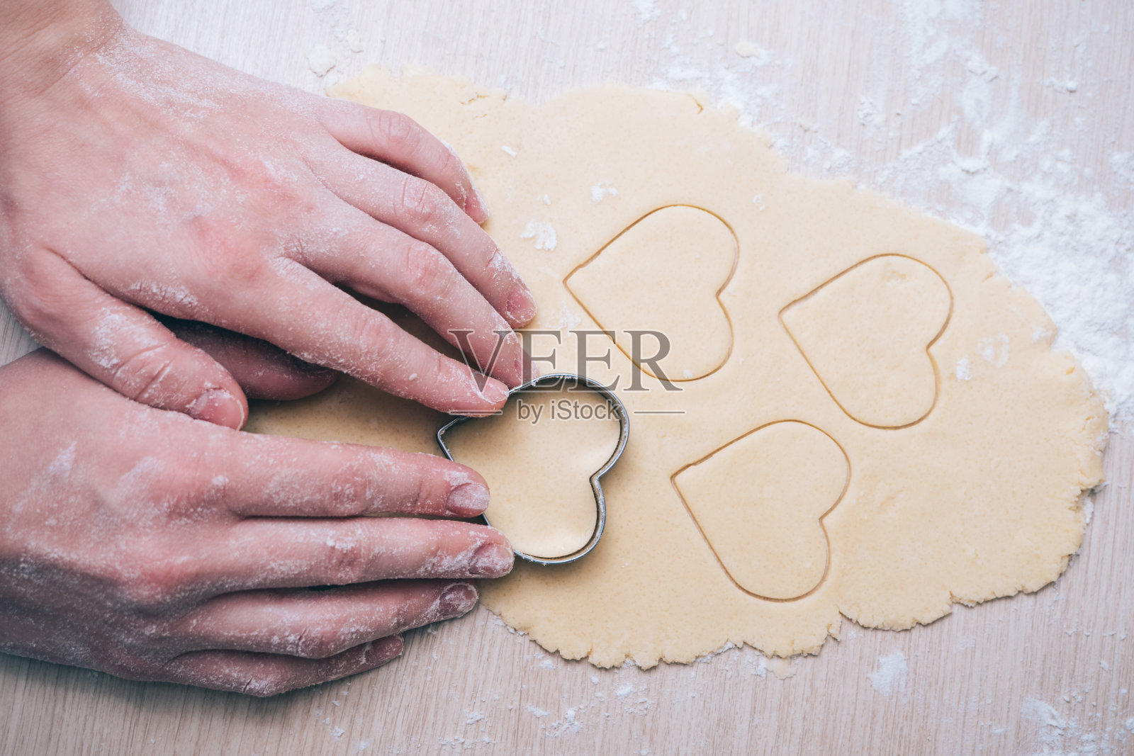 一个女孩在厨房里做心形饼干，特写。在情人节、母亲节或父亲节，给你所爱的人一个惊喜。节日的烹饪背景，与爱照片摄影图片