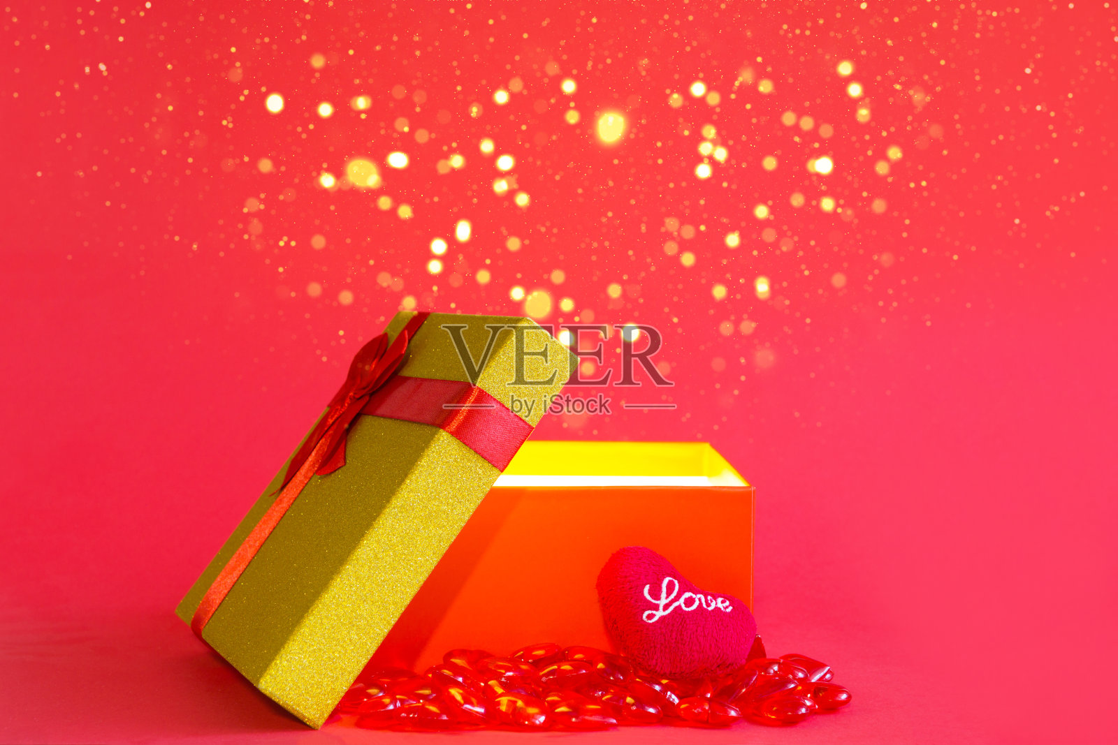 打开红色礼盒与一个蝴蝶结和柔软的心与爱在金色的光芒和闪闪发光在红色的背景，横幅，copyspace里面。四海假日、情人节、新年、生日照片摄影图片