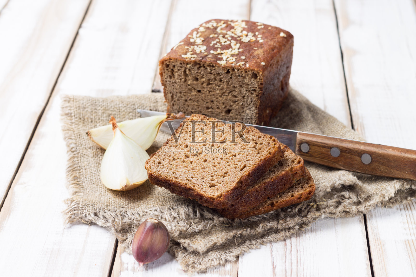 新鲜烘烤的酸面包，由黑麦面粉和洋葱和大蒜在绿色亚麻布餐巾。照片摄影图片