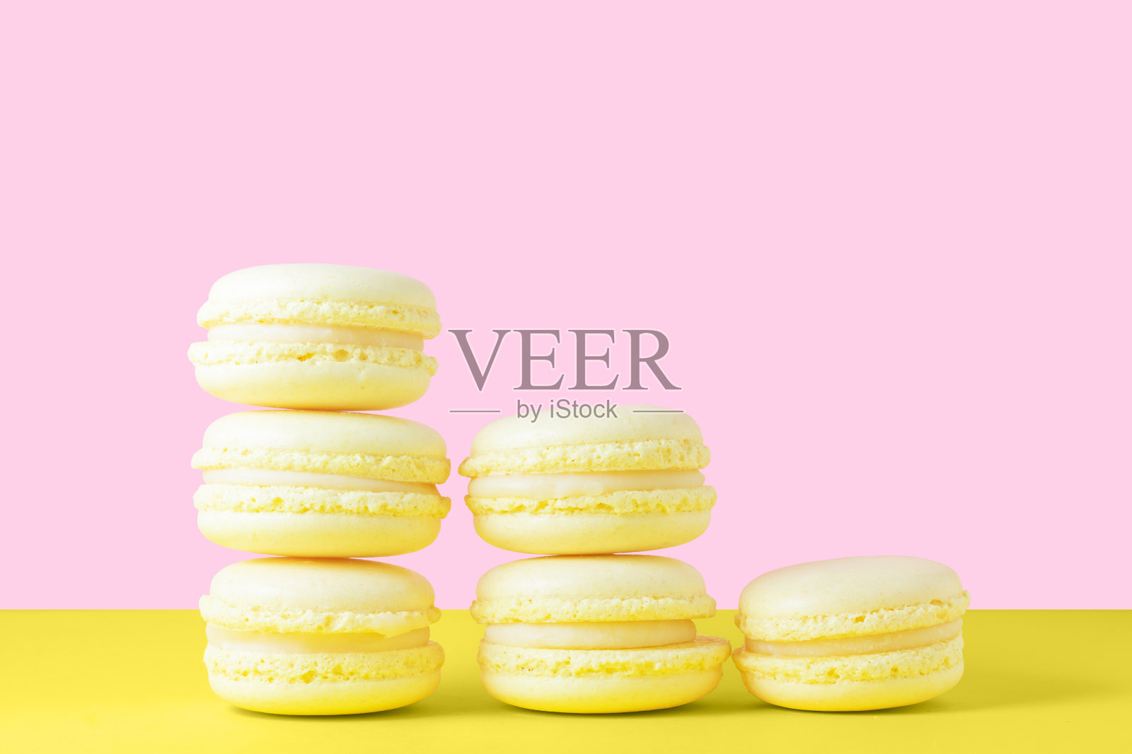 五只黄色的柠檬马卡龙，以黄色和粉红色为背景，呈金字塔状。情人节礼物甜点照片摄影图片