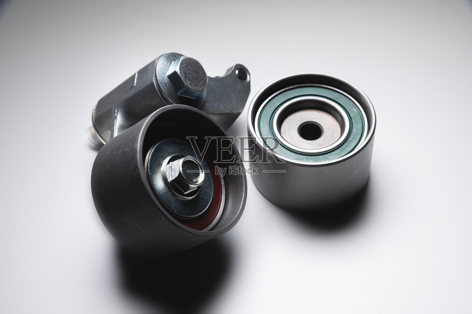 灰色背景上发动机同步带的两个张紧辊。汽车发动机维修的新零件照片摄影图片