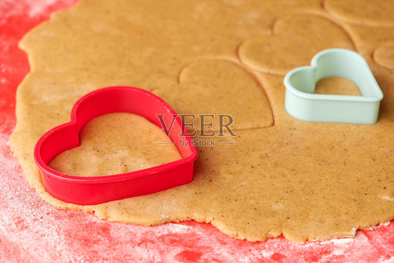 情人节用来做心形饼干的面团。自制的糕点。红色和绿色塑料烘烤模具。照片摄影图片