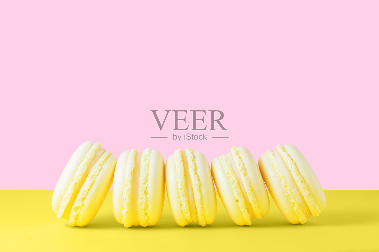 五只黄色的柠檬马卡龙在黄色和粉色的背景上。情人节礼物甜点照片摄影图片