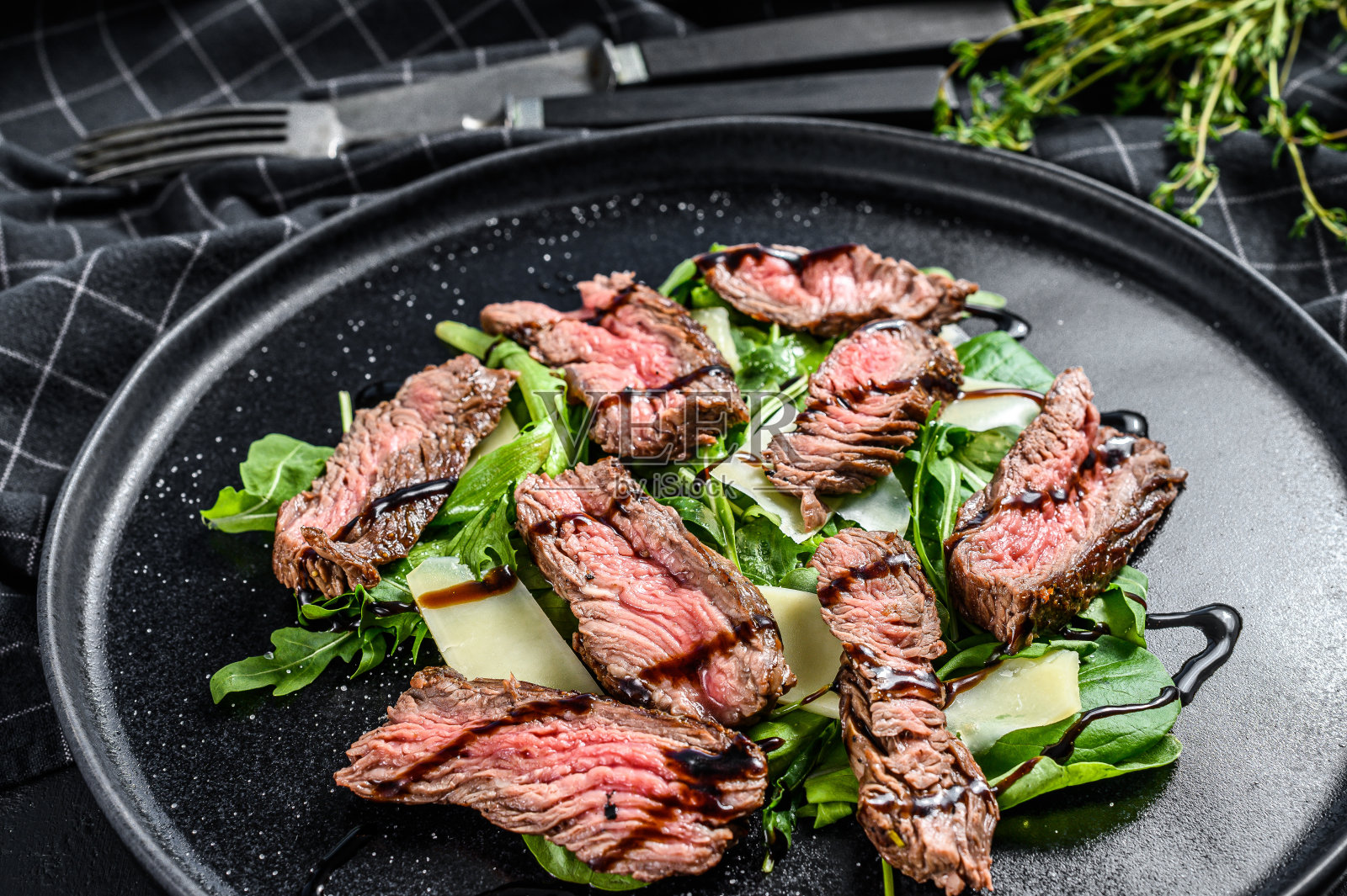 牛排沙拉配菠菜，芝麻菜和牛肉片。黑色背景。俯视图照片摄影图片