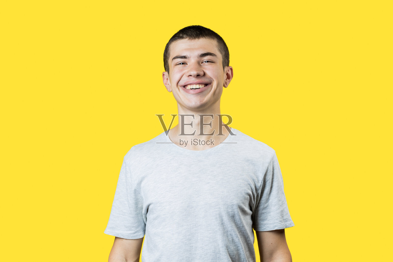 快乐微笑的白人20岁男人在黄色的背景。轻便的衣服。副本的空间。影棚拍摄照片摄影图片