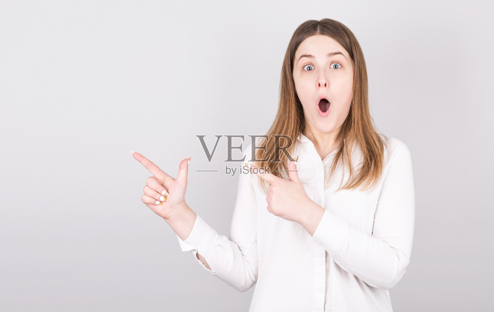 照片上一名惊讶的女子露出震惊的表情，穿着白色t恤映衬着白色的背景。哇的概念。照片摄影图片