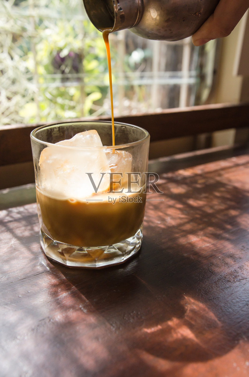 一个咖啡师正在咖啡店的木桌上做冰拿铁咖啡。照片摄影图片