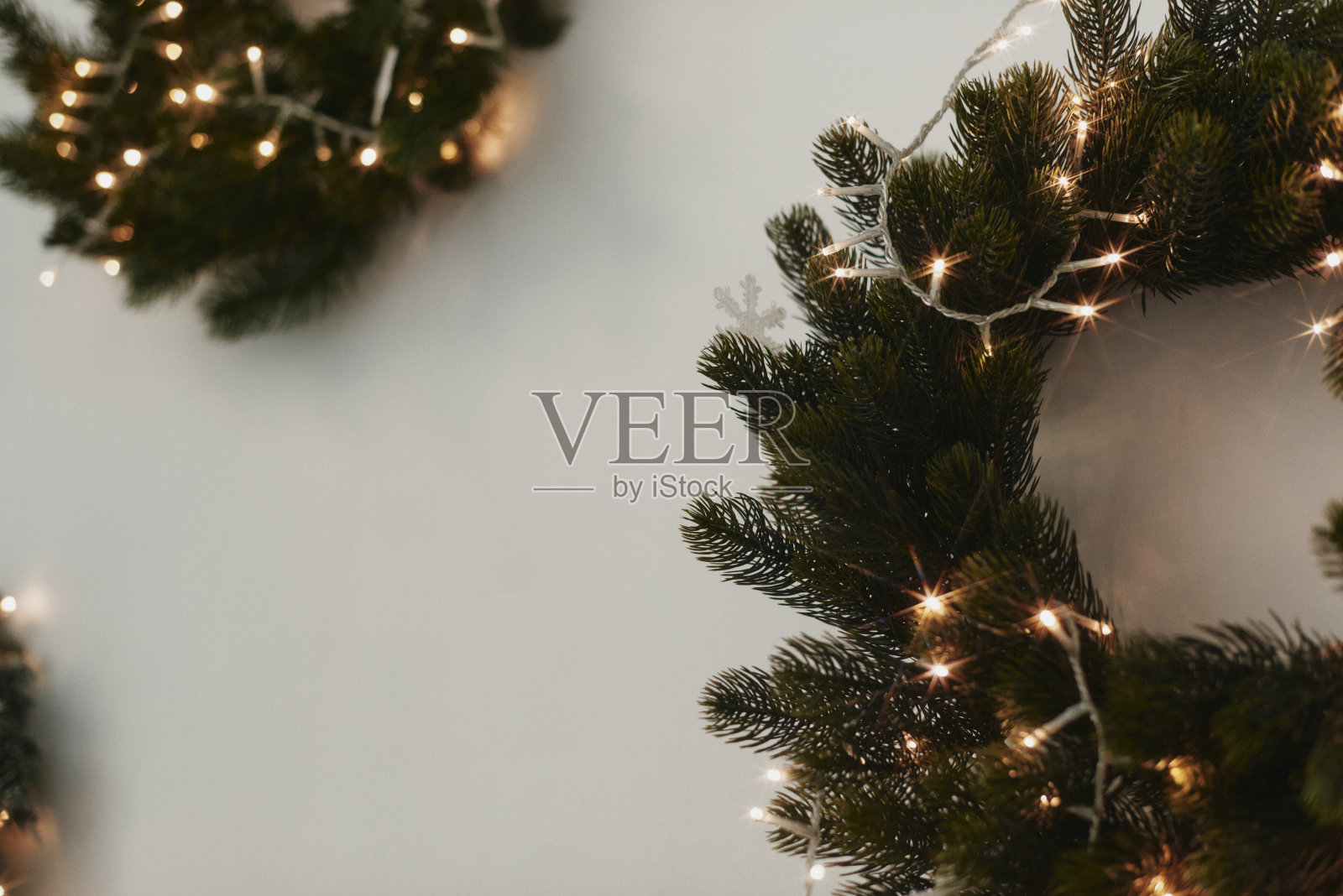 一个传统的明亮的圣诞花环挂在室内的白色墙壁上，是节日的装饰品。圣诞观念，新年观念。空间的文本。寒假手工装饰照片摄影图片