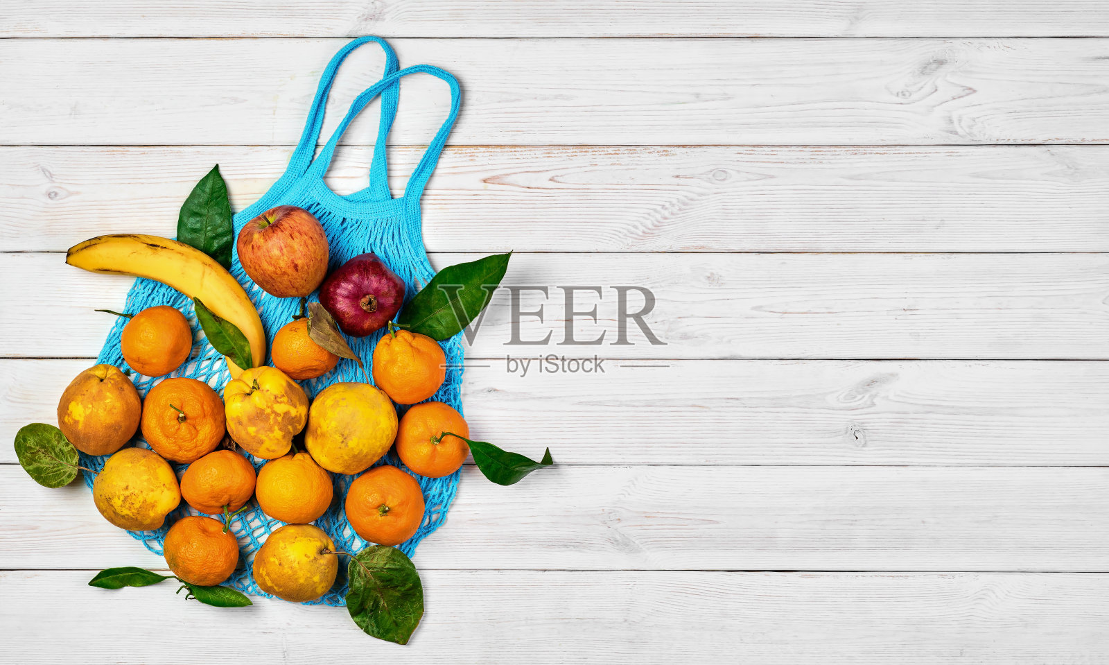 各种熟透的生水果放在碎布网上，供产品放在轻木桌上。从以上观点。零浪费生态食品袋的想法。食品递送、购买或捐赠的概念。模仿与复制空间。照片摄影图片