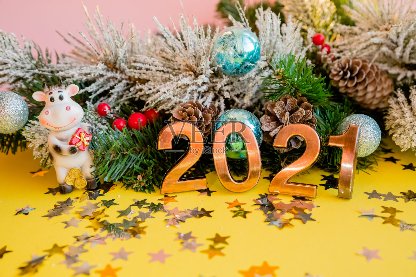 玩具公牛与礼物在一个圣诞树枝的背景。牛是新年的象征。2021年中国新年。冬天的节日庆祝活动。牛年。照片摄影图片