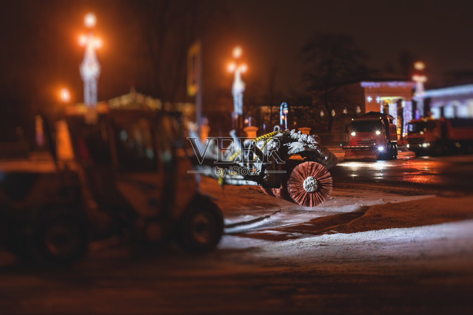 除雪过程在城市的街道和道路上用市政车辆、推土机、扫雪车、扫雪机、除雪设备在冬夜进行照片摄影图片