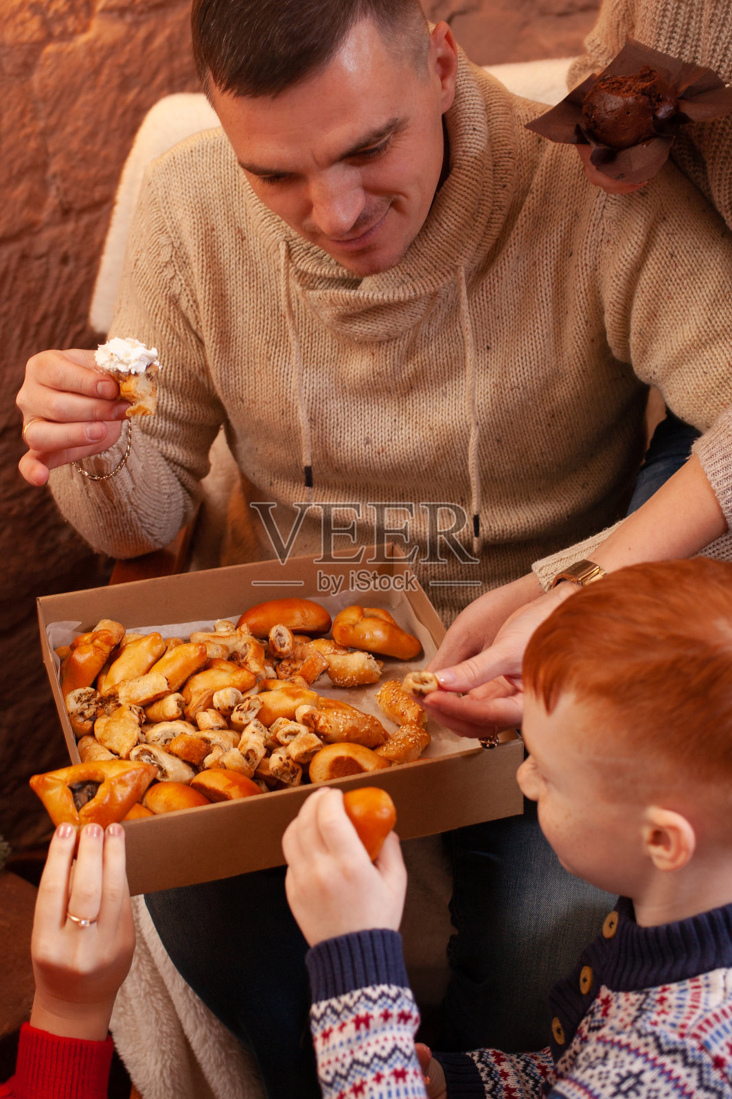 一家人吃盒子里的糕点和糖果。除夕，圣诞树。照片摄影图片