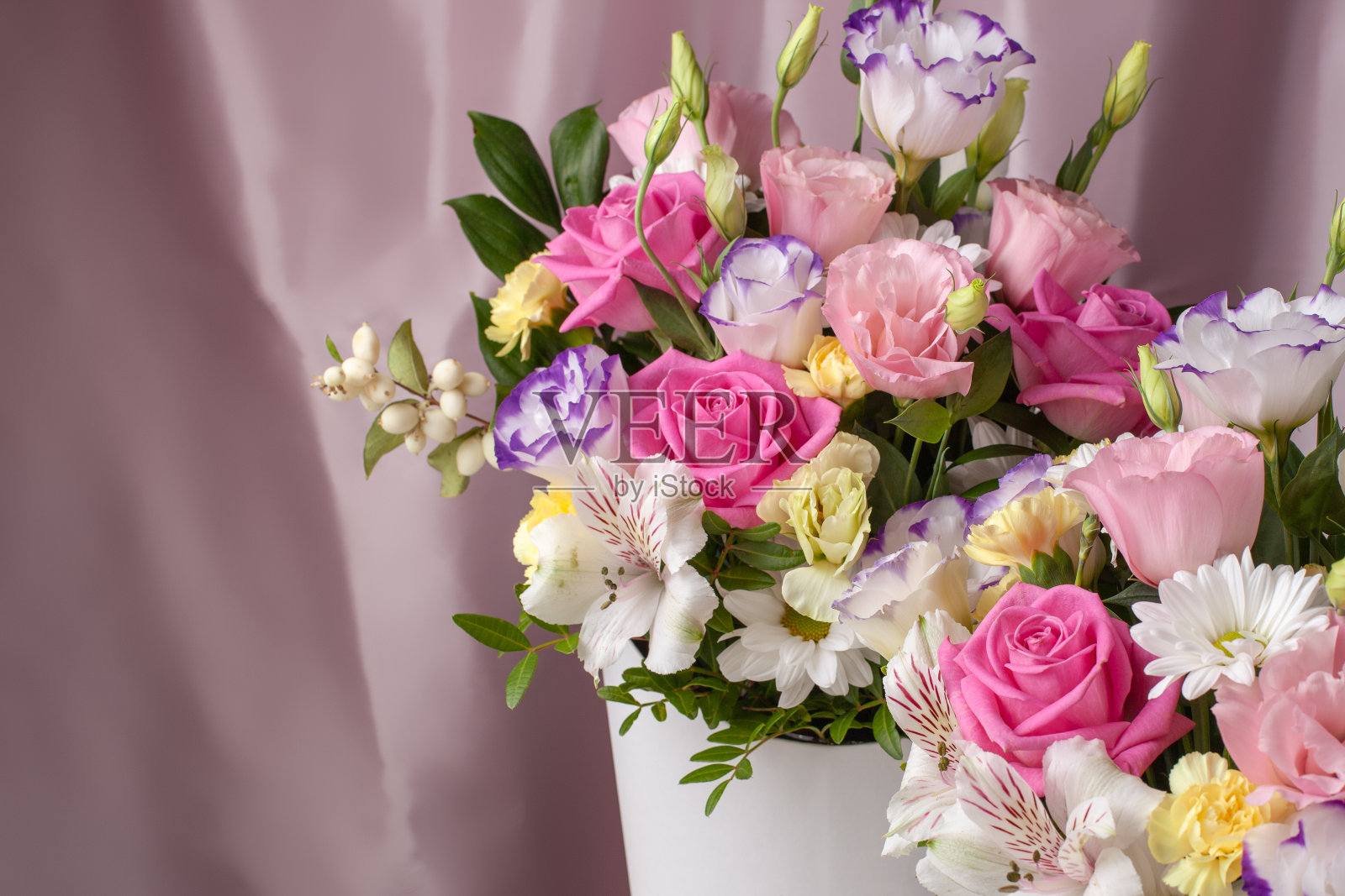 插花玫瑰，雏菊，洋桔梗，菊花，未开的花蕾在粉红色的丝绸织物的背景照片摄影图片