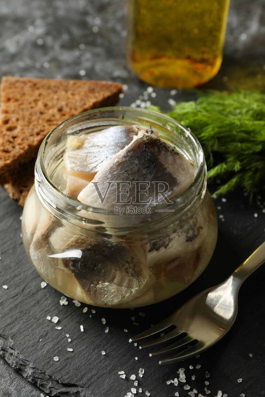 托盘上有鲱鱼，盐，面包和莳萝，以黑烟熏为背景照片摄影图片