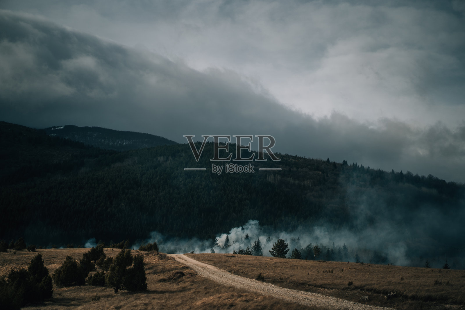 在非城市地区，靠近山区的土地火和烟。波斯尼亚和黑塞哥维那比耶拉斯尼察燃烧的土地上浓烟滚滚照片摄影图片