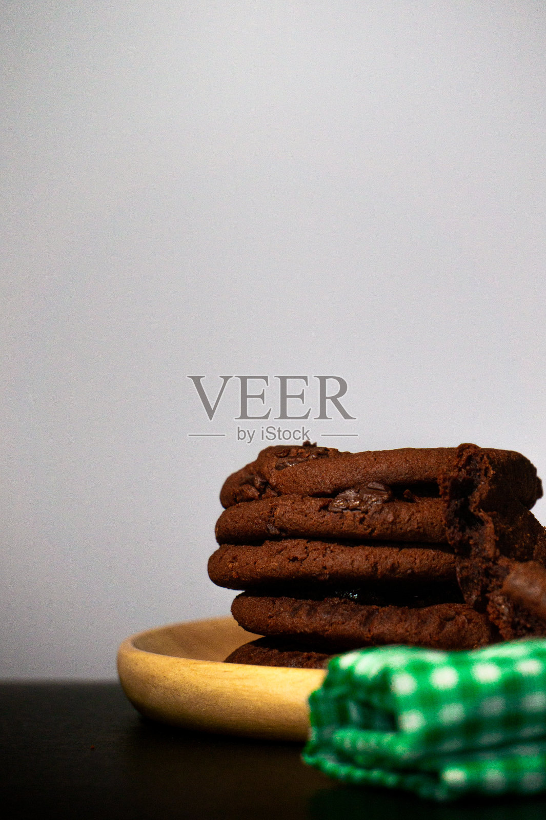 巧克力饼干放在一个木制的托盘里，绿色的布放在黑色的背景上。照片摄影图片