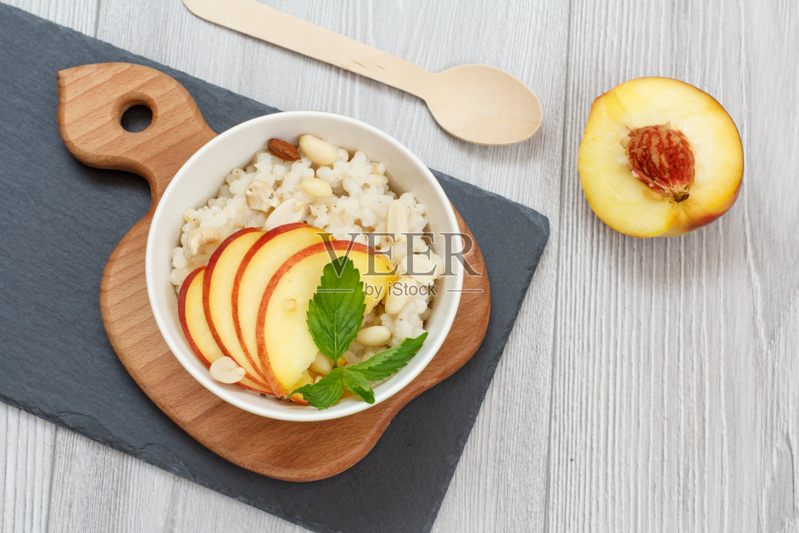 高梁沙拉配果仁和鲜桃在石板上。照片摄影图片