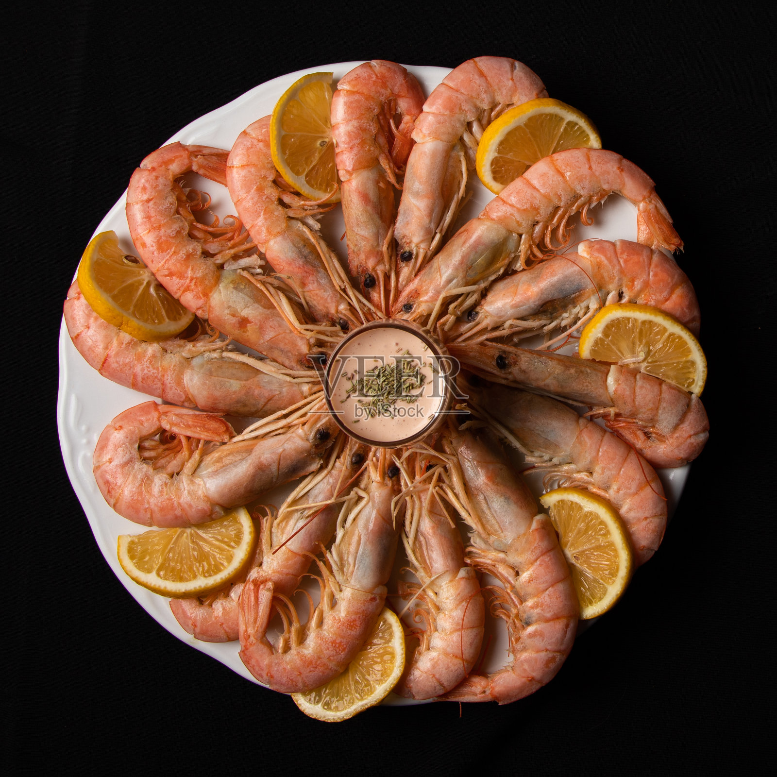 未剥皮的王对虾与柠檬片和鸡尾酒酱一起作为开胃菜或小吃照片摄影图片