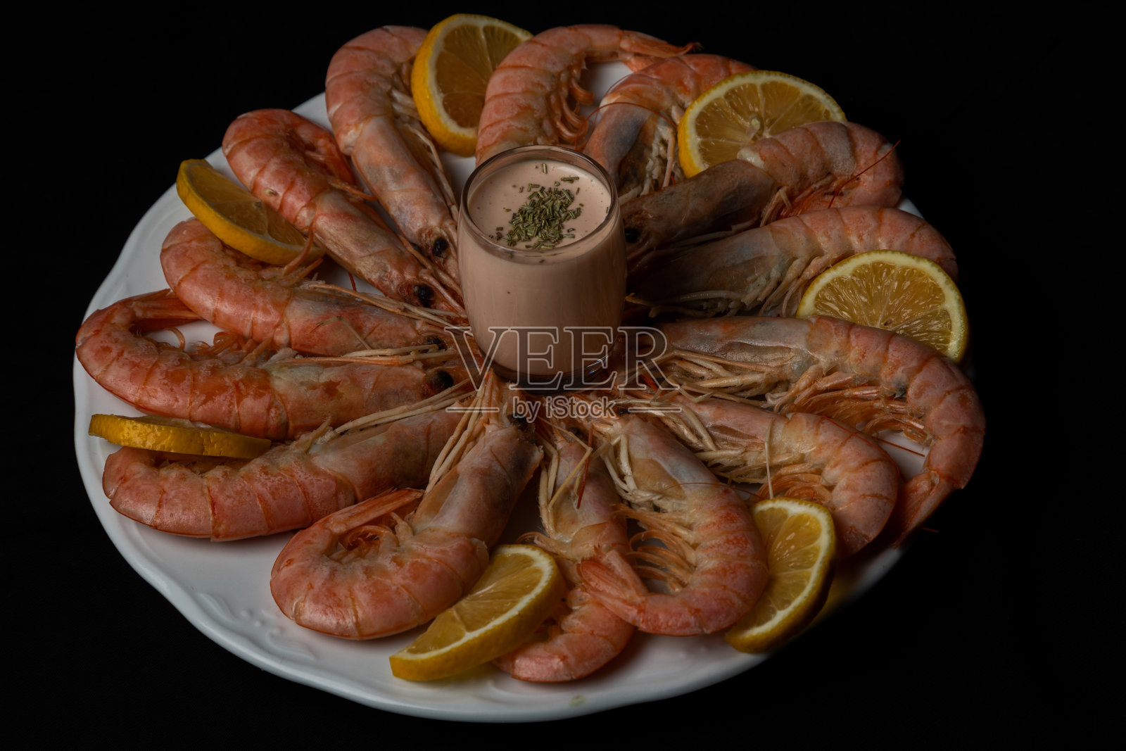 平铺的没有剥皮的大虾配上柠檬片和鸡尾酒酱，作为开胃菜或小吃照片摄影图片