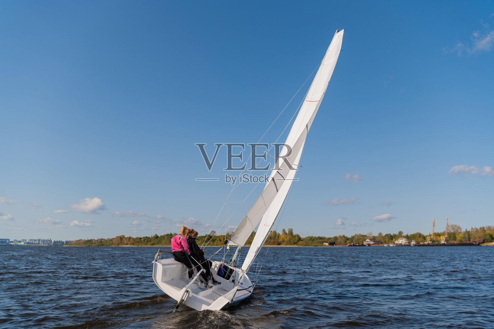 一位年轻的航海教练和两个女新手在一条风景优美的河上上课照片摄影图片