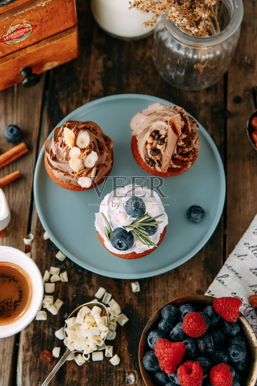 甜点有奶油、蓝莓和巧克力。在木桌上摆放甜点和坚果。照片摄影图片