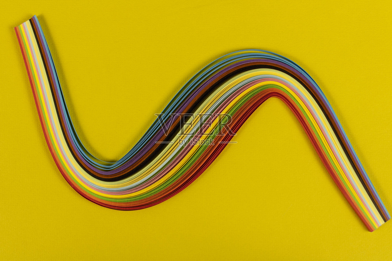 黄色背景上的彩色羽毛纸。抽象的背景纹理。照片摄影图片