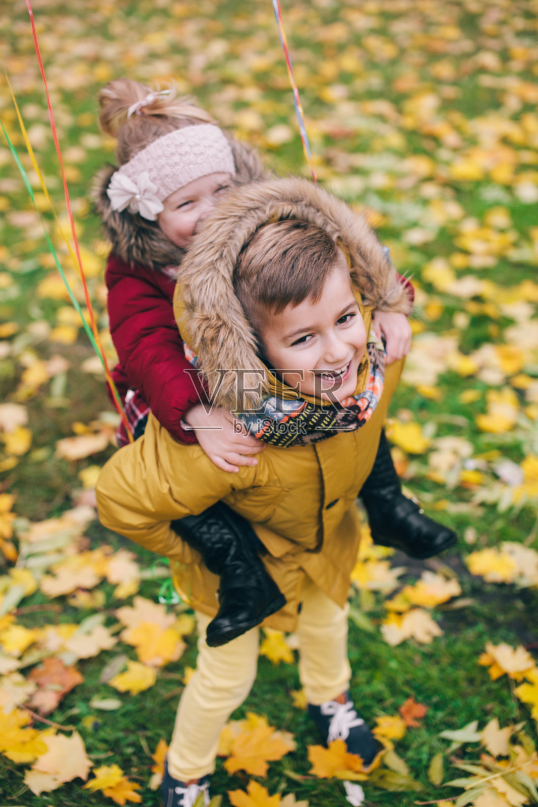 秋天，哥哥在公园里骑着他的小妹妹照片摄影图片