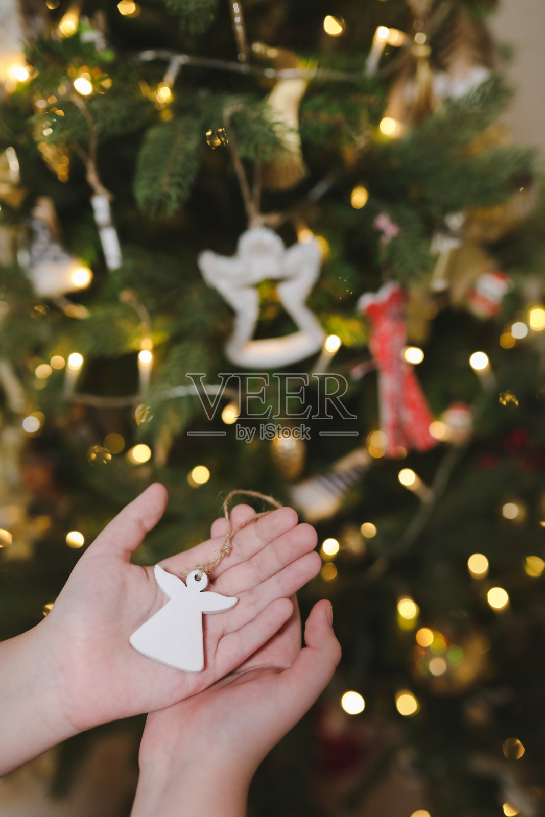 装饰圣诞树，手拿圣诞玩具。假日、圣诞节和新年的家庭庆祝概念照片摄影图片