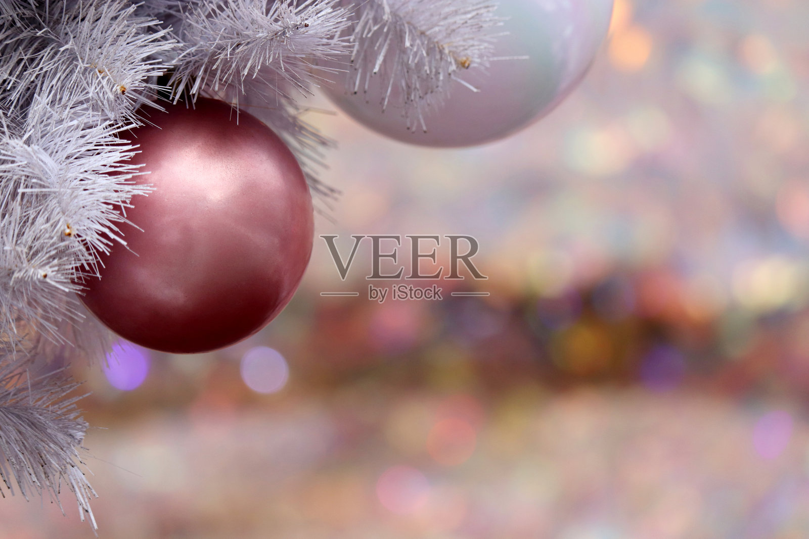 粉红色和白色的圣诞球挂在冷杉树枝上，在节日的灯光背景下照片摄影图片