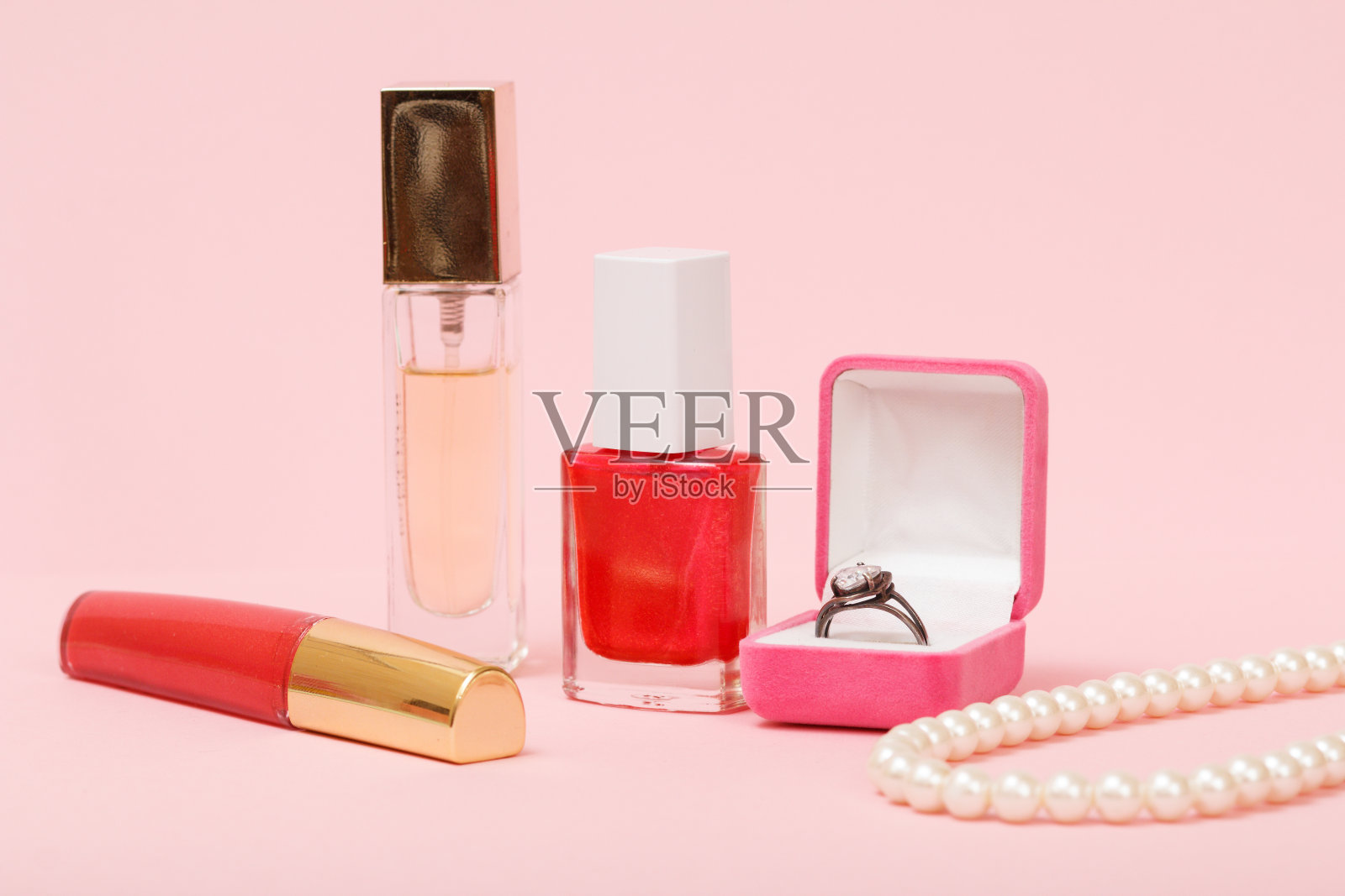 口红，香水，指甲油和粉色背景的戒指盒。照片摄影图片
