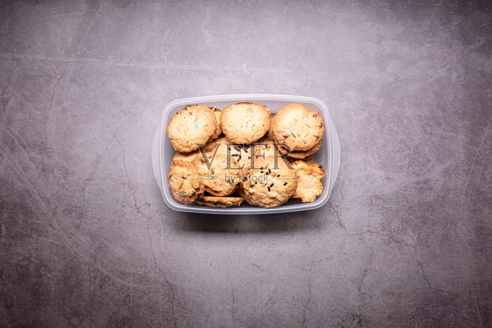 一些自制的饼干放在一个塑料盒子上，在灰色的背景上仍然孤立照片摄影图片