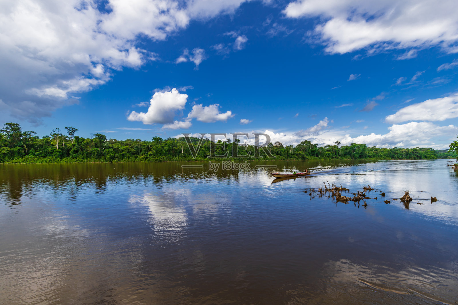 晴朗的一天，云朵倒映在苏里南河上，一只小船驶过照片摄影图片