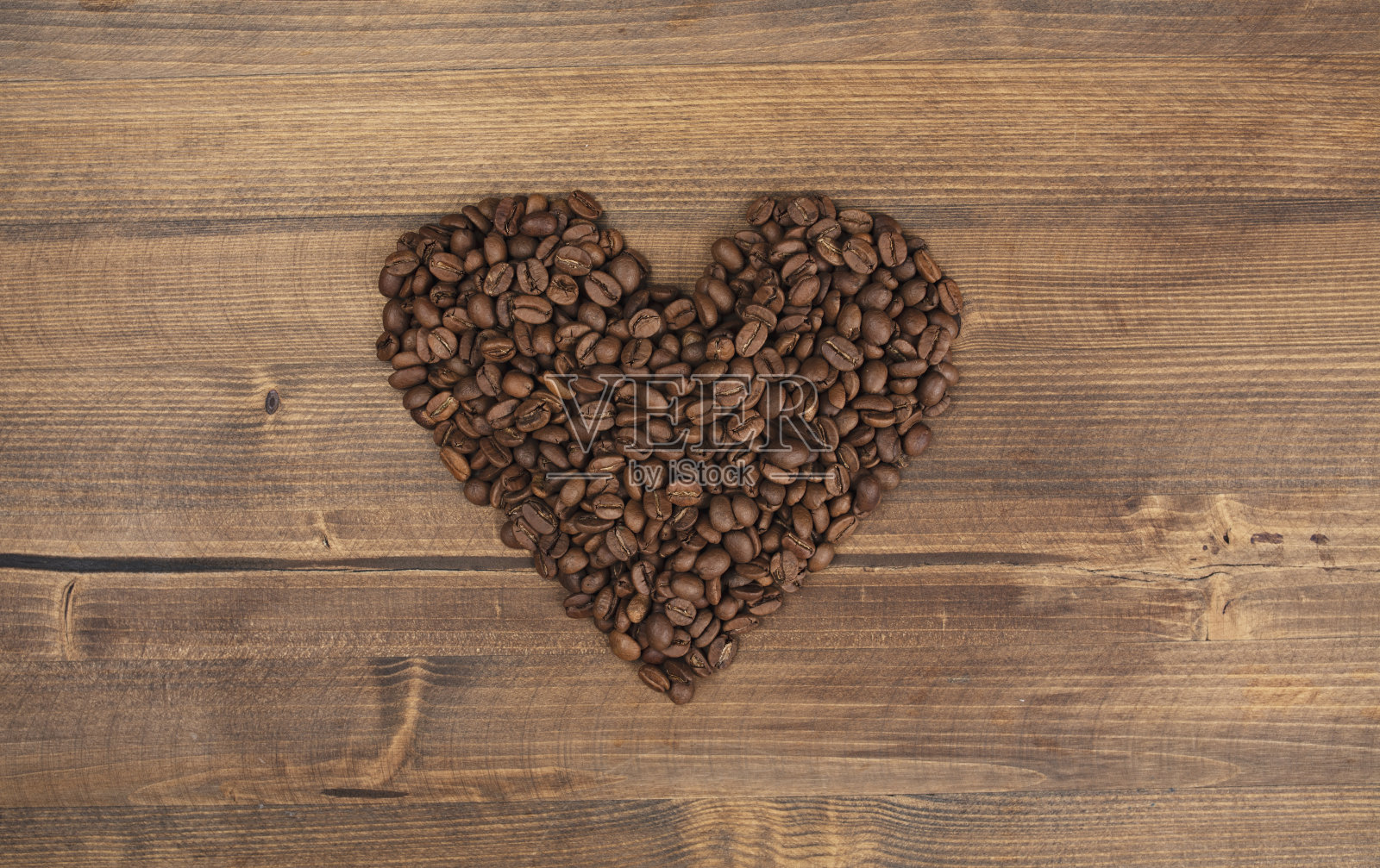 咖啡与烤生咖啡豆做一个心形的木制背景。照片摄影图片