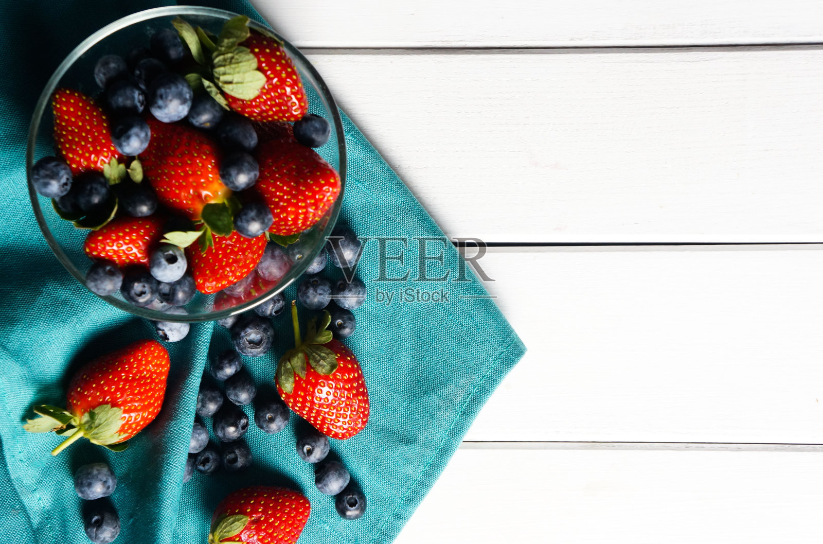 新鲜的草莓和蓝莓散落在一个玻璃碗里照片摄影图片