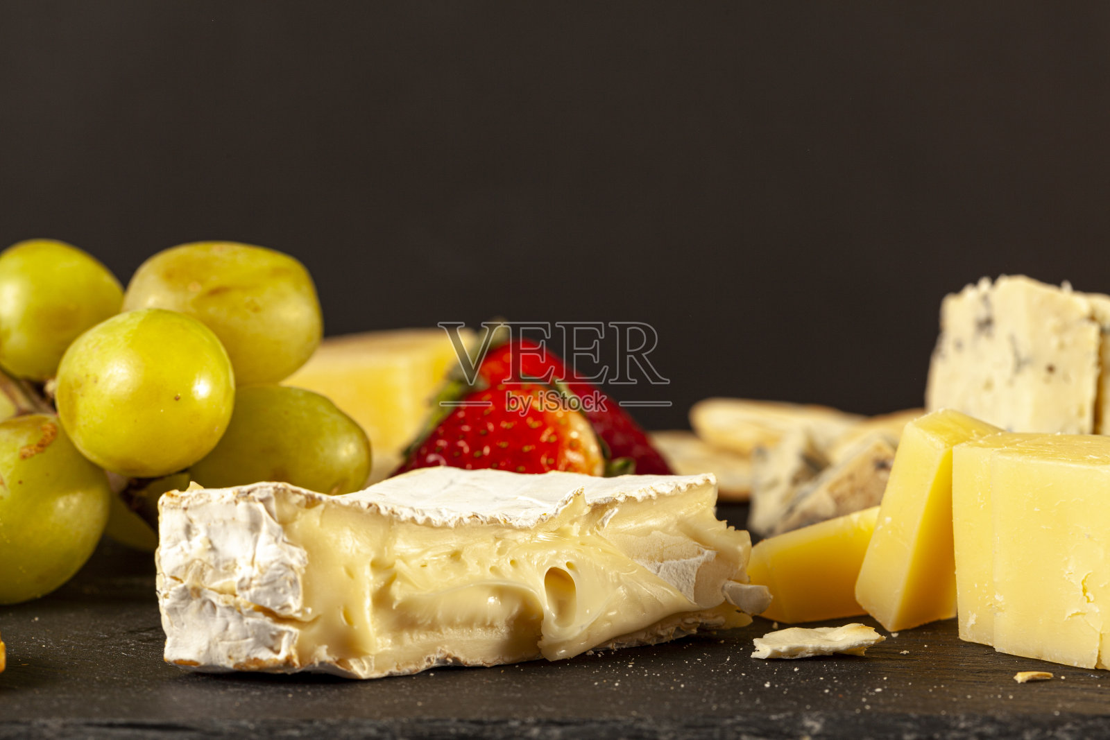 工匠奶酪拼盘与饼干和水果在黑奶酪板照片摄影图片