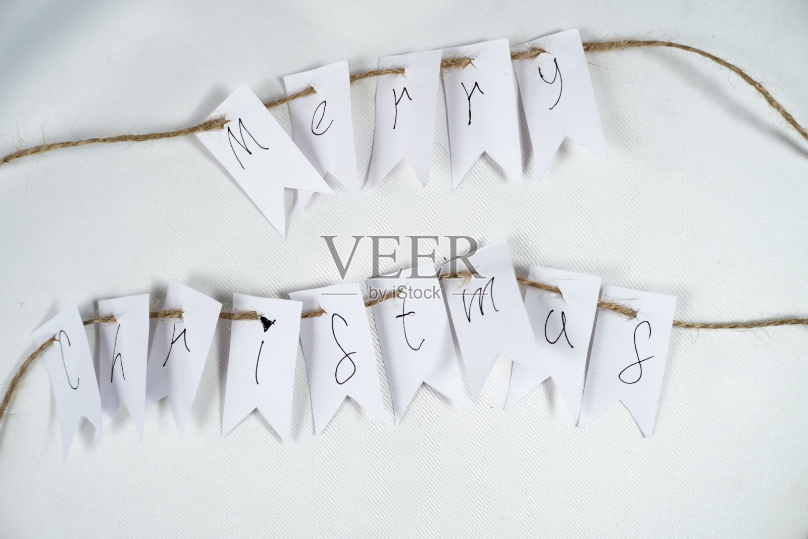 用棕色线和白色背景的白色床单上的字母写着圣诞快乐的短信照片摄影图片