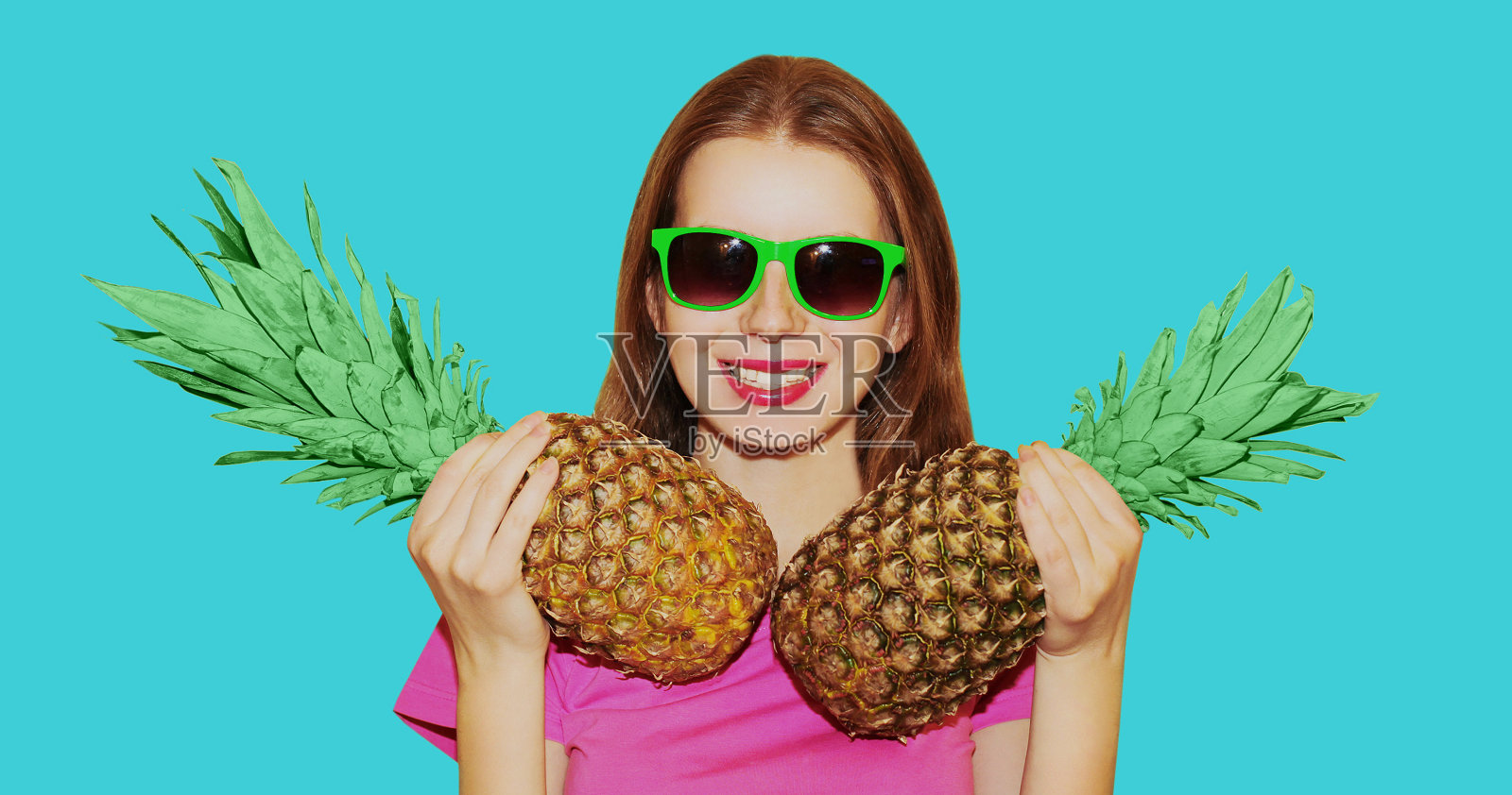 快乐微笑的女人肖像与菠萝戴太阳镜孤立在一个蓝色的背景照片摄影图片