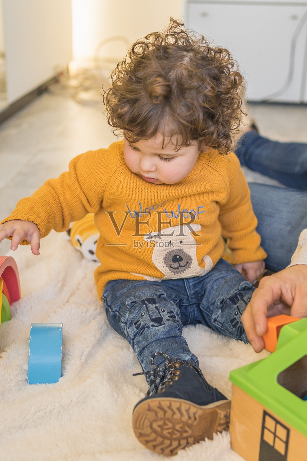 穿着金黄色毛衣的孩子独自在家里的房间里玩照片摄影图片