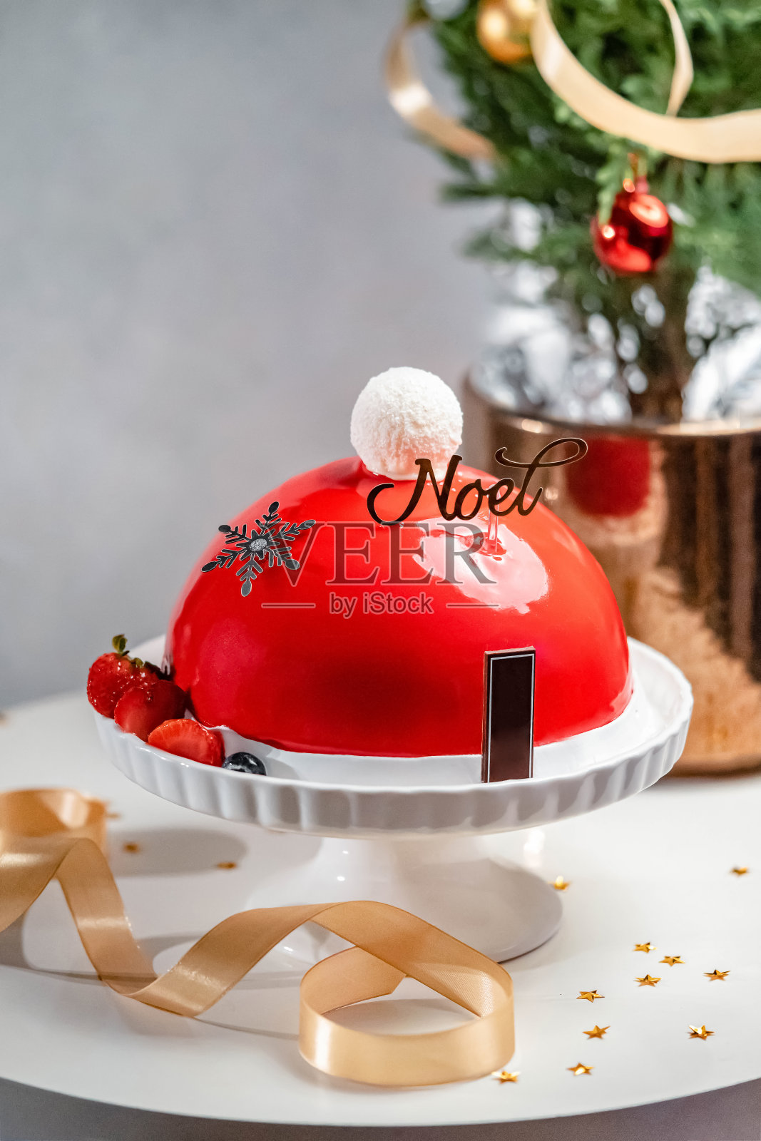诺埃尔圣诞节红草莓蛋糕上有圣诞老人的帽子形状的白色背景照片摄影图片