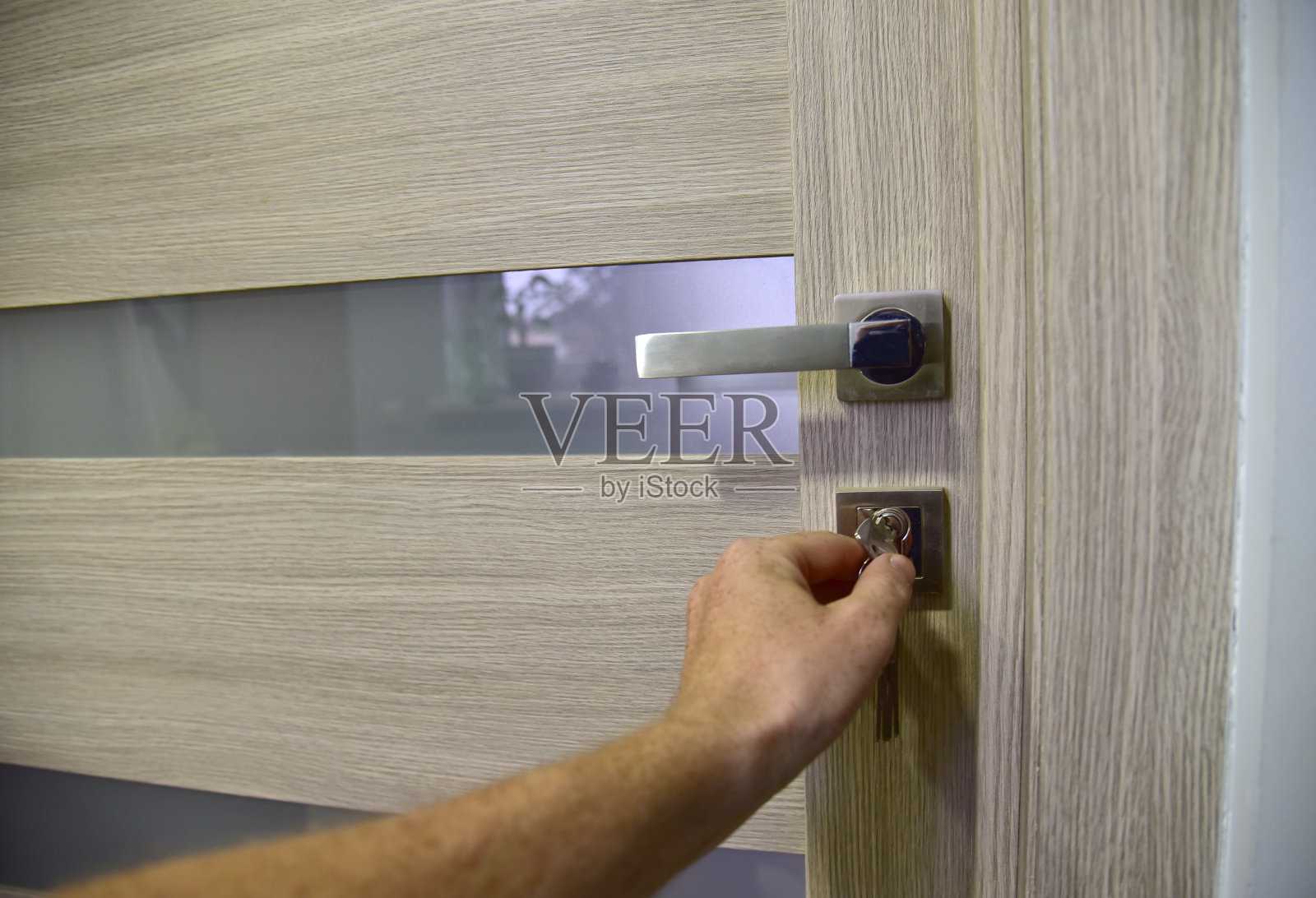 用钥匙手动开门。带锁和钥匙的家门在房间里关闭照片摄影图片