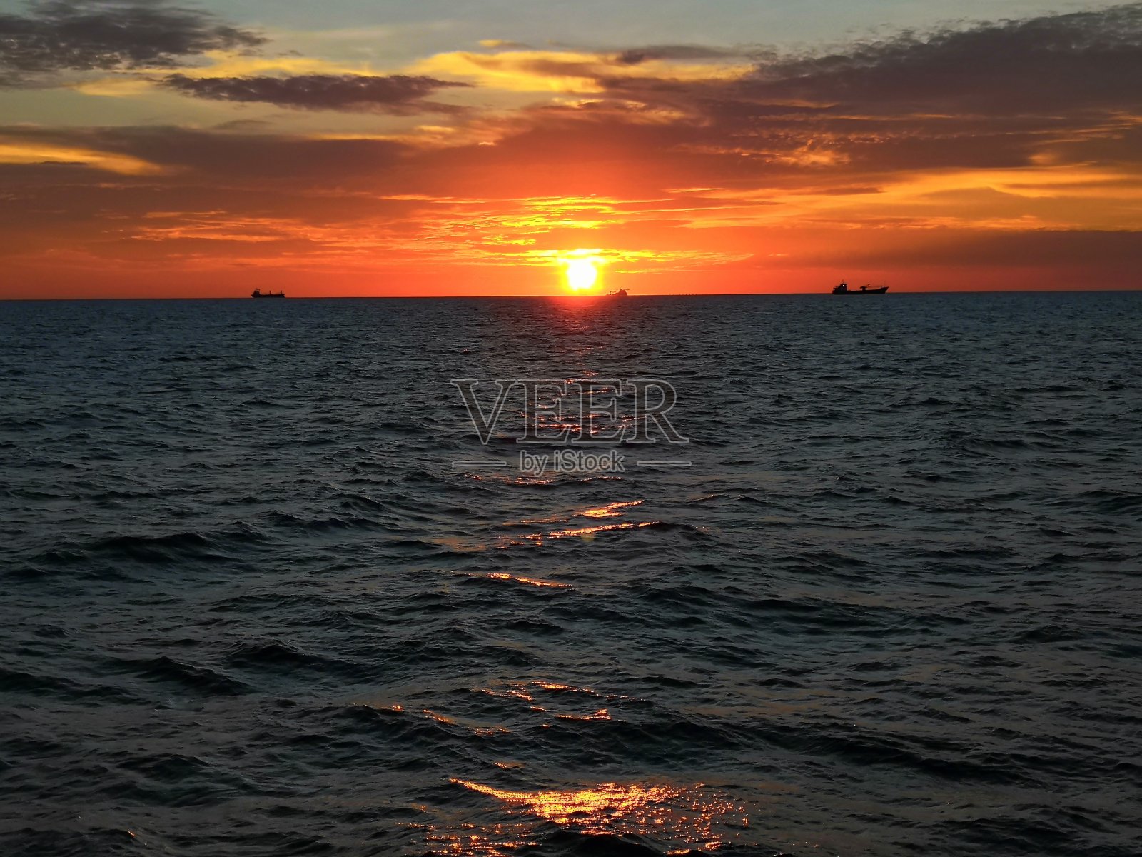 美丽的日落在大海中央照片摄影图片