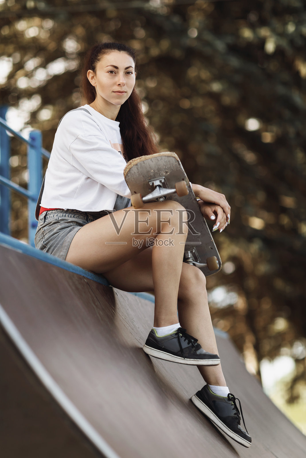 年轻女子在骑车前手里拿着滑板休息照片摄影图片