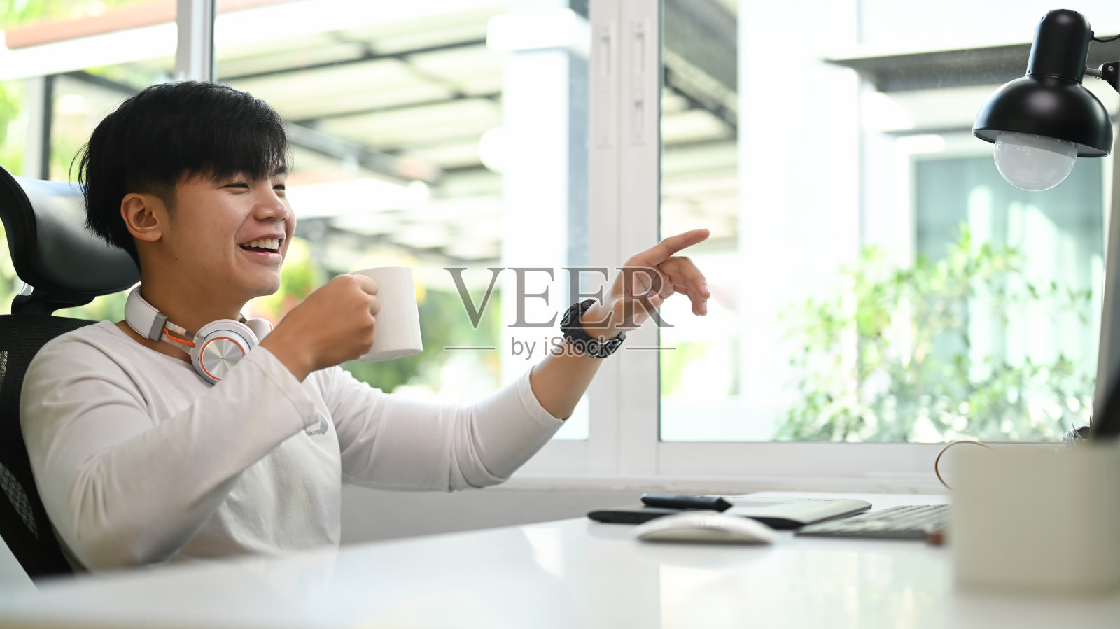 年轻的自由职业者穿着休闲装在家里喝着咖啡和他的同事进行视频通话。照片摄影图片