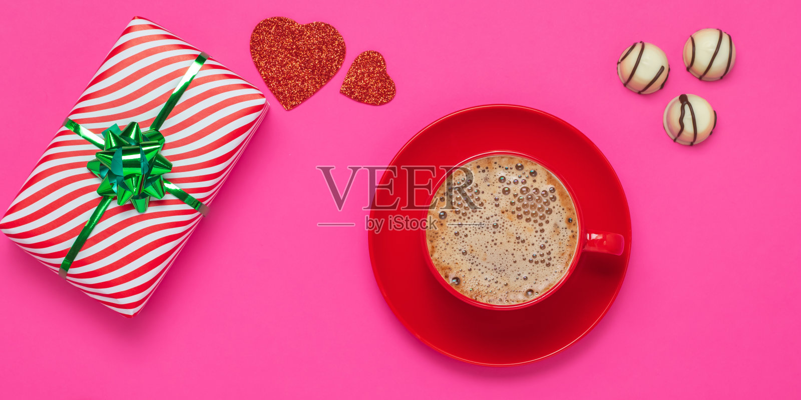 情人节或圣瓦伦丁节的概念。礼物和泡沫拿铁，红心和白巧克力糖果。浪漫的粉色卡。早上要一杯红杯和一碟热饮。照片摄影图片