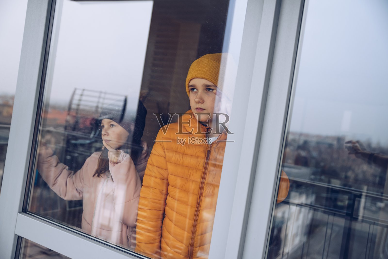 孩子们站在窗口，想念他们的朋友，学校和正常的生活。照片摄影图片